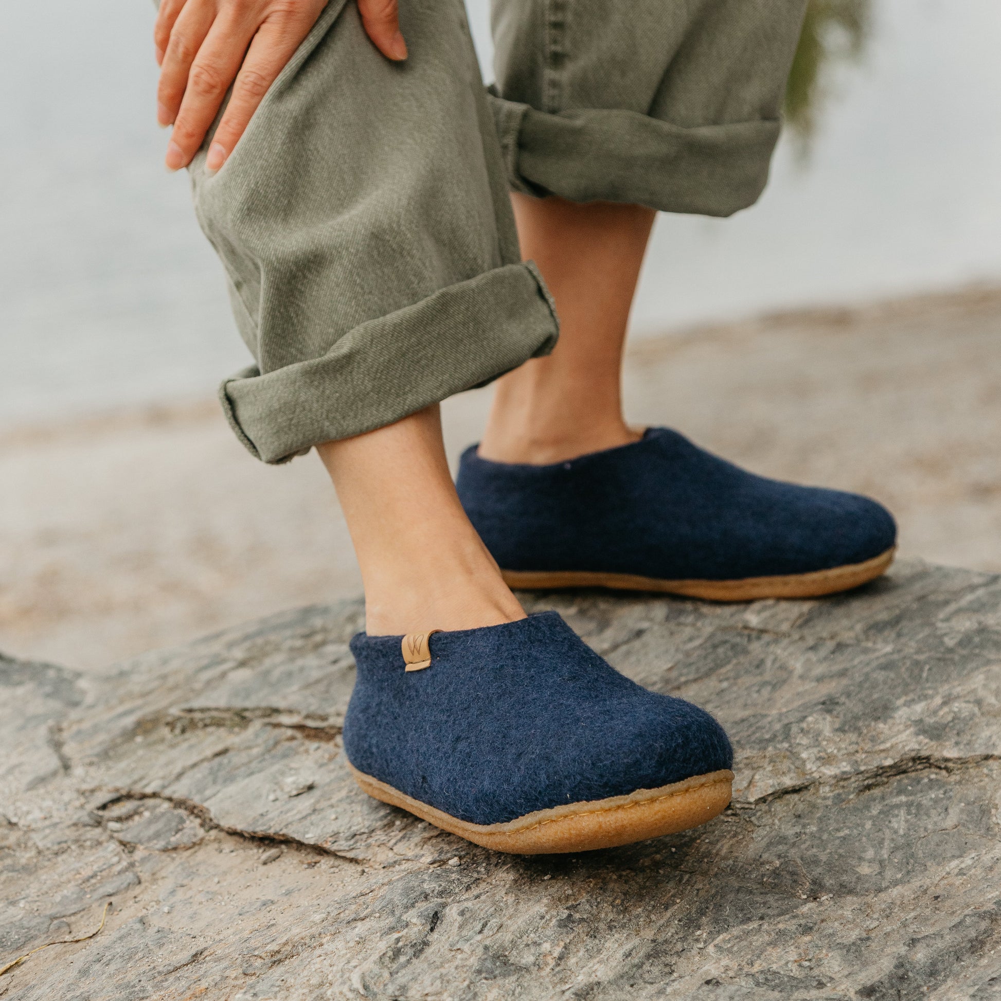 Person wearing navy blue shoes standing on a rock with a blurred natural background